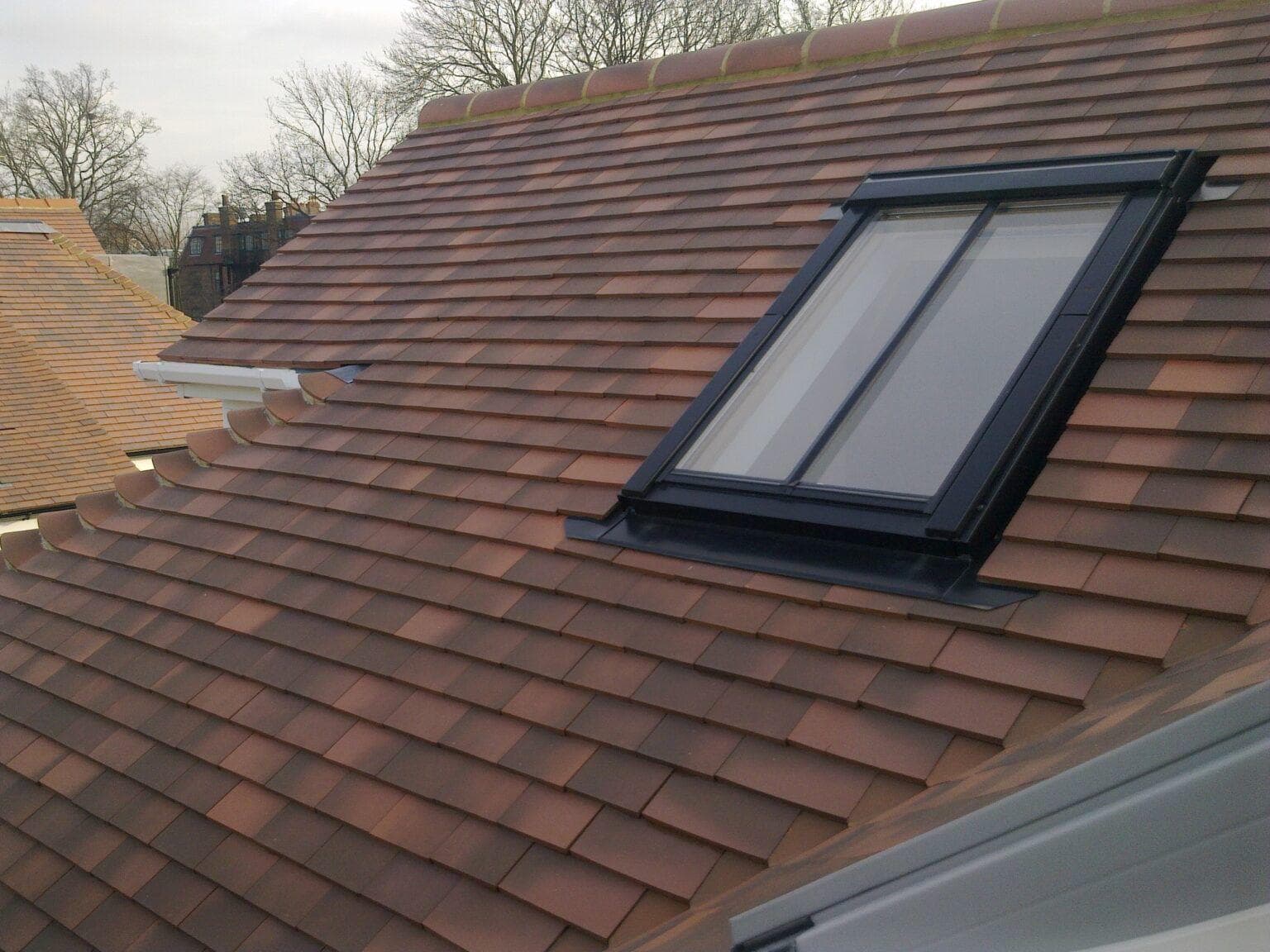 Velux window installation with clay roof tiles